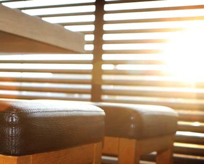 Interieurdetail met houten lamellen, warm gouden tegenlicht en lederen barkrukjes